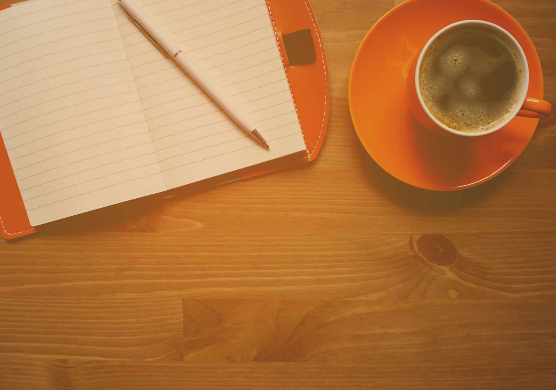 Eine Tasse Kaffee neben einem offenen Notizbuch, eine ruhige Stimmung am Morgen.